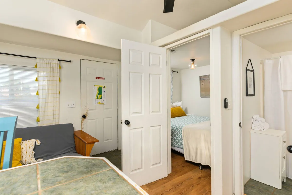 A view of a cheerful dining table set near an open door leading to the bedroom, complemented by stylish light fixtures and comfortable seating. The space feels communal and inviting, giving a sense of togetherness and comfort, perfect for travelers returning from an outdoor outing with pets.